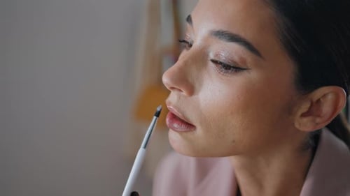 Nahaufnahmemodell, das zu Hause Lippenstift aufträgt. Visagistin, Frau, Gesicht, zeichnet Lippen