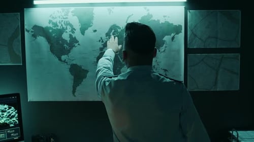 Man Examines World Map in Dark Office