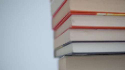 A stack of books on a bright background. Front view of the books and fast movement from bottom to to