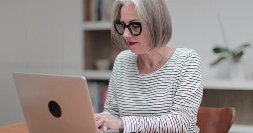 Mature adult female paying bill online using a laptop