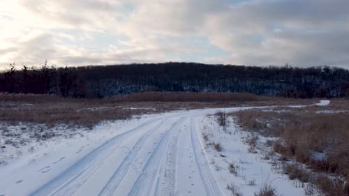 Fly forward above snowy white road in countryside