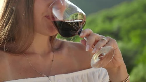 Elegant lady enjoys a glass of red wine in a closeup shot on a tranquil villa terrace