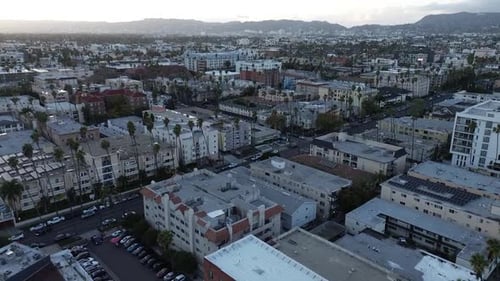 Push in drone shot across dense urban neighborhood in Los Angeles during golden hour.