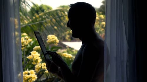 Silhouette of Happy Man Browsing Web on Tablet by Terrace Window, Super