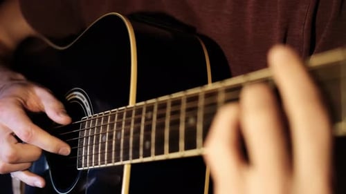 Man Plays Black Acoustic Guitar with Detailed Fretboard View
