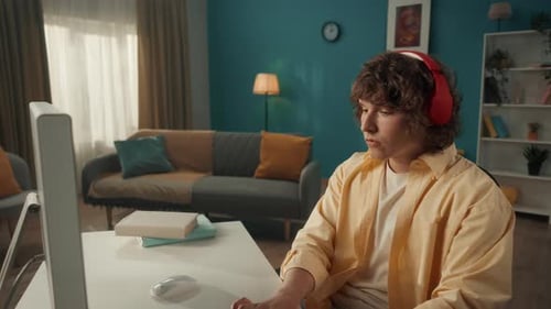 Young Adult Works at Computer in Home Office