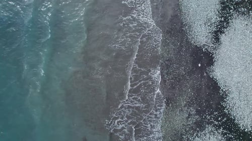 Aerial View of Clear Blue Ocean Waves Crashing on Rocky Beach Shore