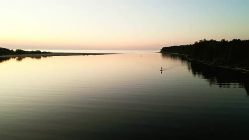 Person Paddleboarding on Still Lake at Sunrise