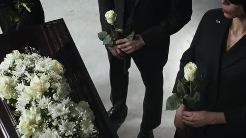 People Pay Respects at Funeral with Flowers