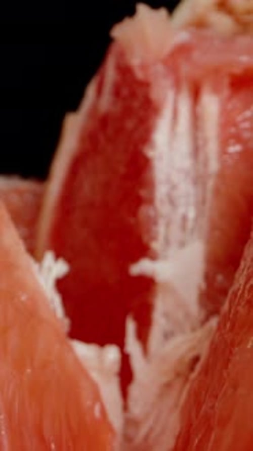 Vertical video. Whole and sliced grapefruits on the table. Inside with red flesh. Dolly slider, clos