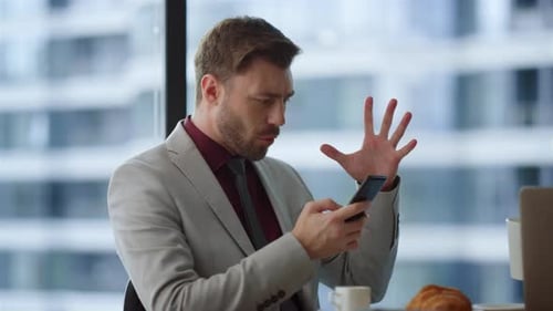 Excited man celebrates success with phone in office