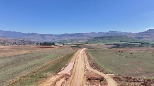 Dirt road heading towards Cathedral Peak and Amphitheater of Drakensberg Mountains in South Africa