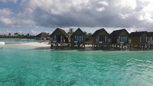 Drone voa em direção ao spa de villas aquáticas em um resort nas Maldivas. Água azul e turquesa. Full HD