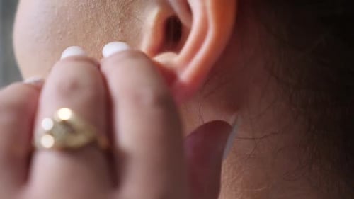 Woman Putting on Sparkling Silver Dangle Earring