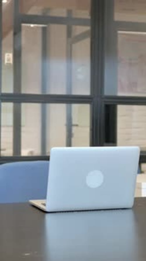 Young Adult Opens Laptop at Desk Indoors