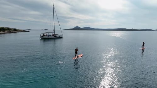 Standup Paddleboarding In The Sea Near The Yacht. - aerial shot