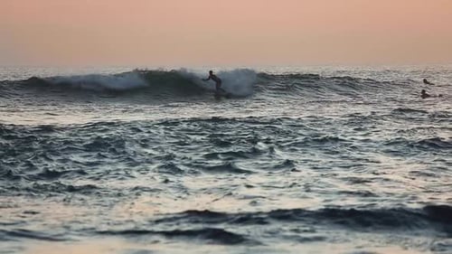 Un surfeur surfe sur les vagues à Bali, en Indonésie, au coucher du soleil - Ralentissement