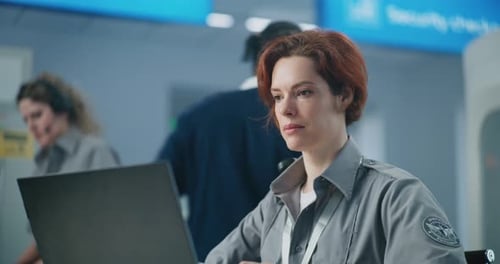 Airport Security Checkpoint Serious Female Security Officer Using Laptop Looking at Camera