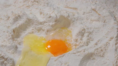 Adding Egg to Flour Baker in Bowl Close Up Shot of Pouring Egg in Well Mound Flour for Cooking a