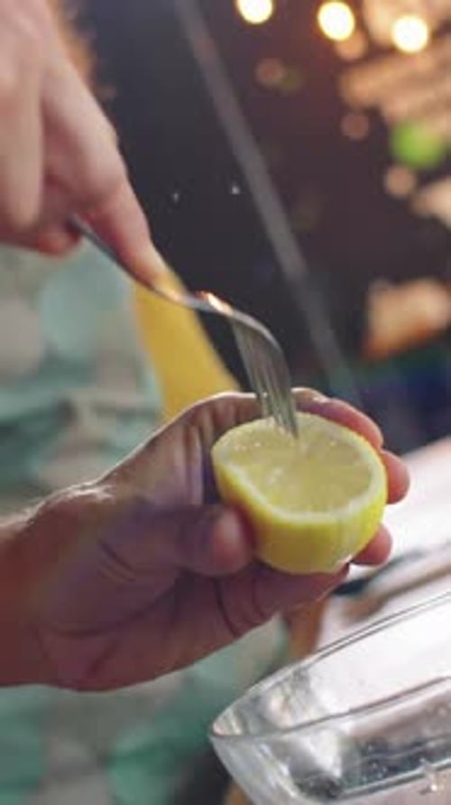 Squeezing Lemon with Fork into Water Glass Indoors