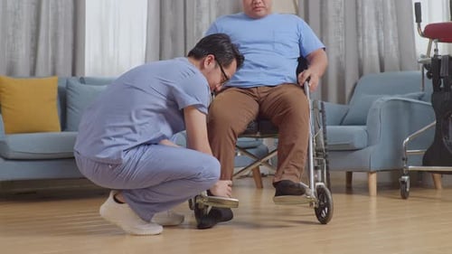 Physical Therapist Adjusting Wheelchair Footrests for Patient