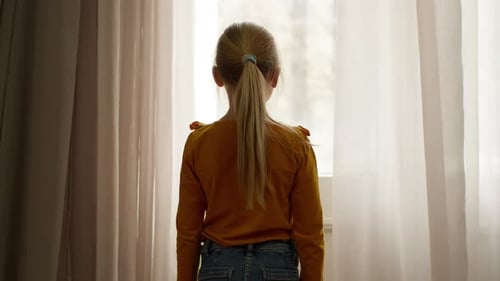 Back View Caucasian Little Girl Child Kid Daughter Looking Out Window at Street Outside Dreaming