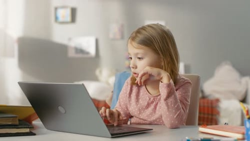 Young Girl Typing on Laptop at Desk