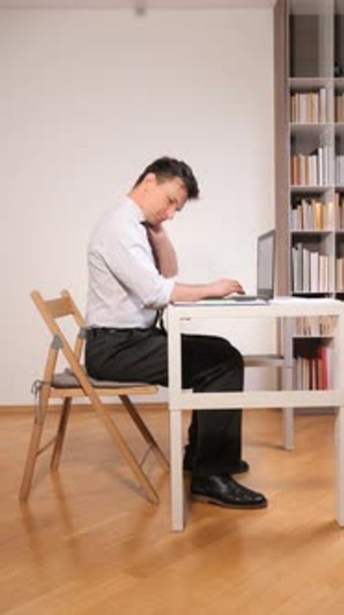 Vertical Video Businessman Experiencing Discomfort and Stress From Poor Posture While Working on a