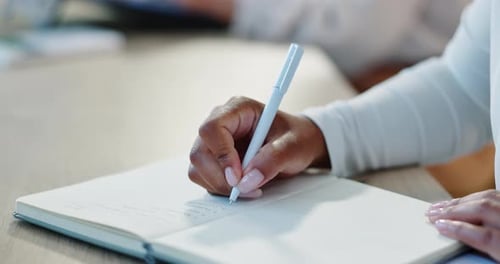 Person Writing in Notebook at Work Meeting