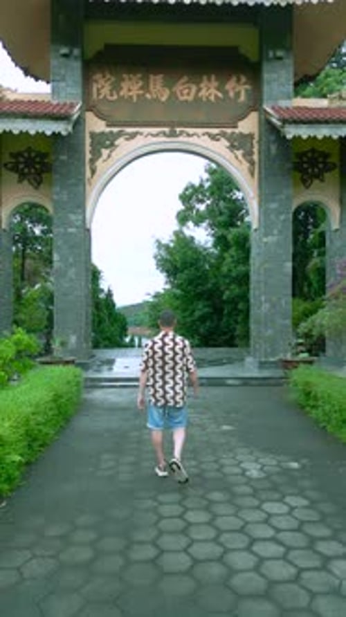 Une vue aérienne d'un homme marchant vers un magnifique temple bouddhiste au Vietnam entouré de luxuriants