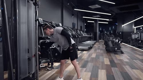 Fitness man trains on modern simulators in a modern gym slow motion