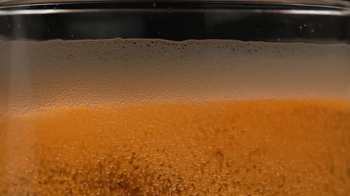 Bolhas em um copo de cerveja em macro 240 fps. Bolhas sobem no copo e criam espuma de cerveja