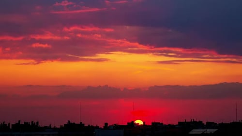 Sonnenuntergang über den Dächern der Stadt bei bewölktem Himmel
