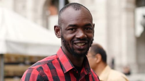 young African man in the street smiles at the camera