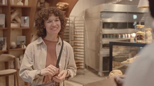 Female Customer Picking Up Takeaway Order at Bakery