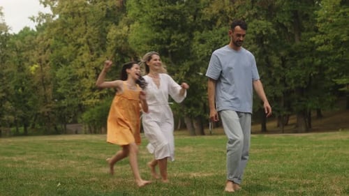 Happy Family Walks Barefoot in Park Enjoying Time Together