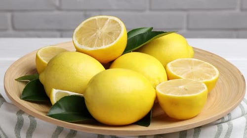 Bright Yellow Lemons on Wooden Plate with Leaves