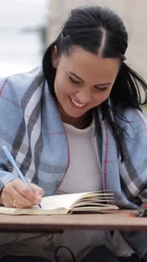 Smiling Woman By Table Happily Writing Notes Sharing Fun with Lively Gestures