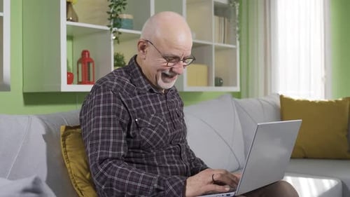 Senior Man Typing on Laptop at Home