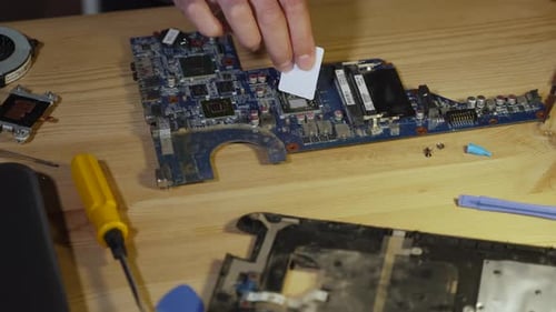 Man with Spatula Evenly Distributes Thermal Paste Over Surface of Processor