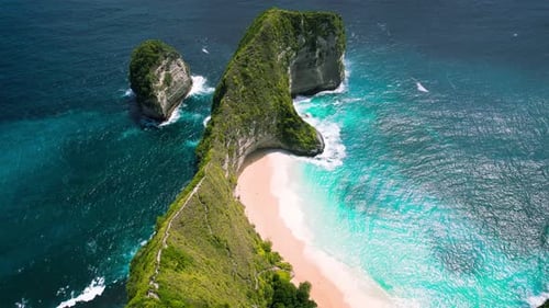 Ocean waves roll on pristine white sandy shore of Kelingking beach in Bali Indonesia.