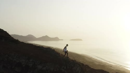 Tracking guy running down slope of mountain ridge with bright sunrise