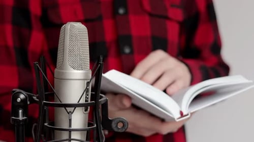 Close up of man flipping through a book near a microphone. Recording audiobook using microphone.