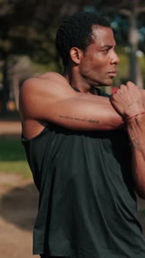 Vertical video, Fit Black Man Stretches in Park