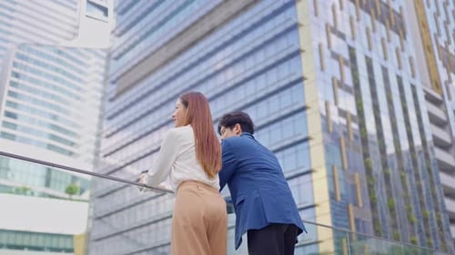 Rear view of businessman and woman partner working outdoors in the city.
