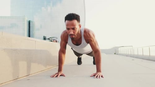 Young athlete doing workout, push ups on the embankment