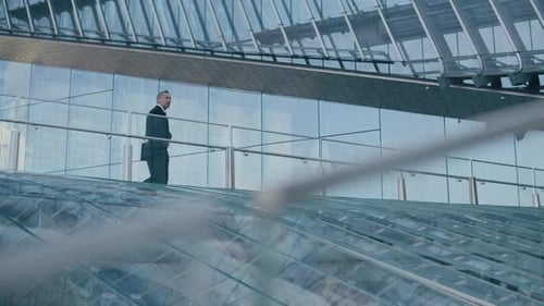 Middle-aged Entrepreneur Walking along Glass Balcony outside Office Building