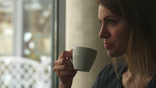 Woman Drinks Hot Coffee By Window