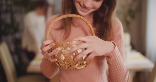 Young Girl Holding Easter Eggs In Basket At Holiday Table