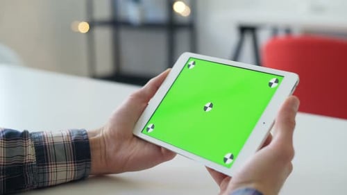 Young Man Browsing Tablet with Green Screen